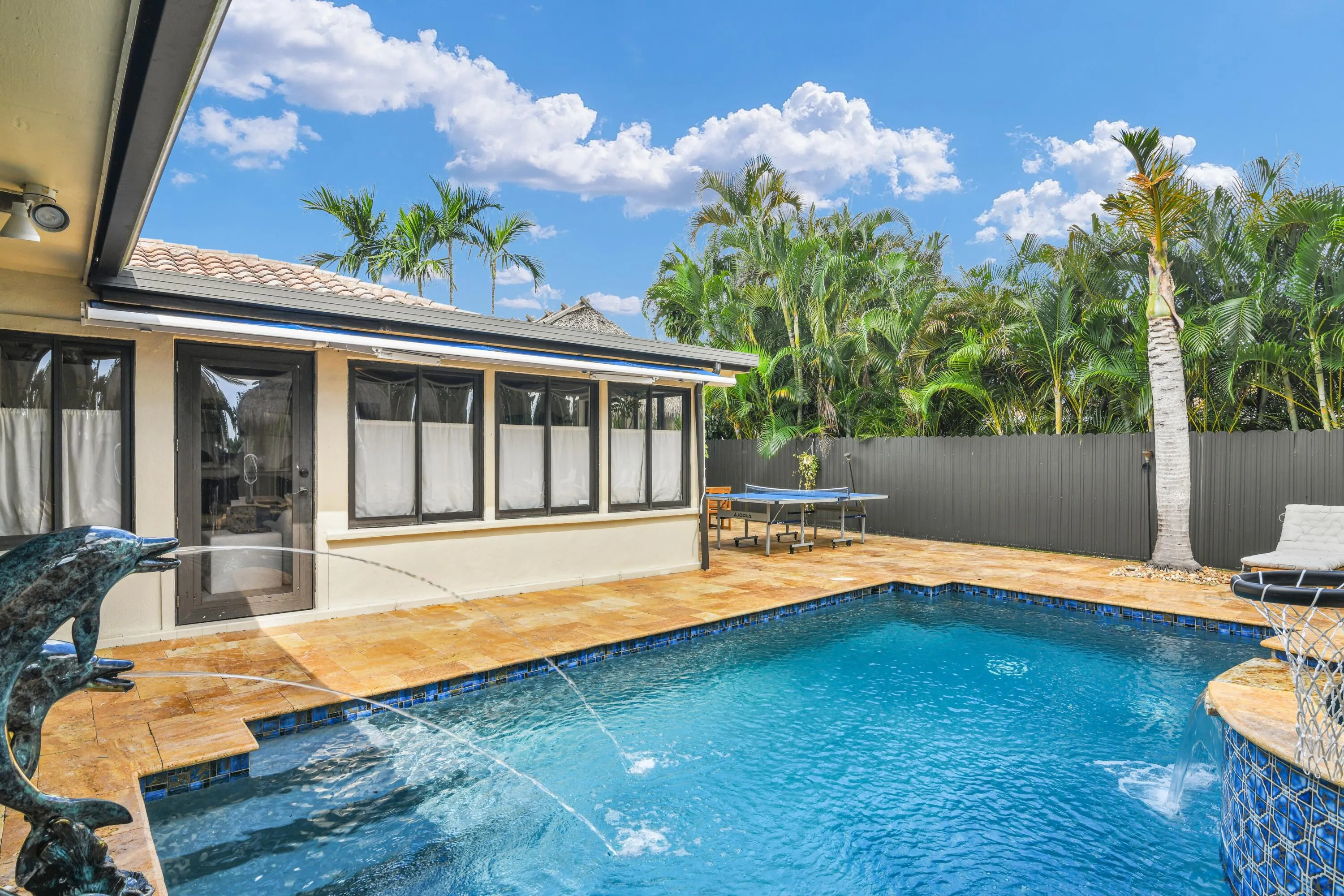 Swimming pool with blue mosaic tile, surrounding paved patio, and privacy fencing