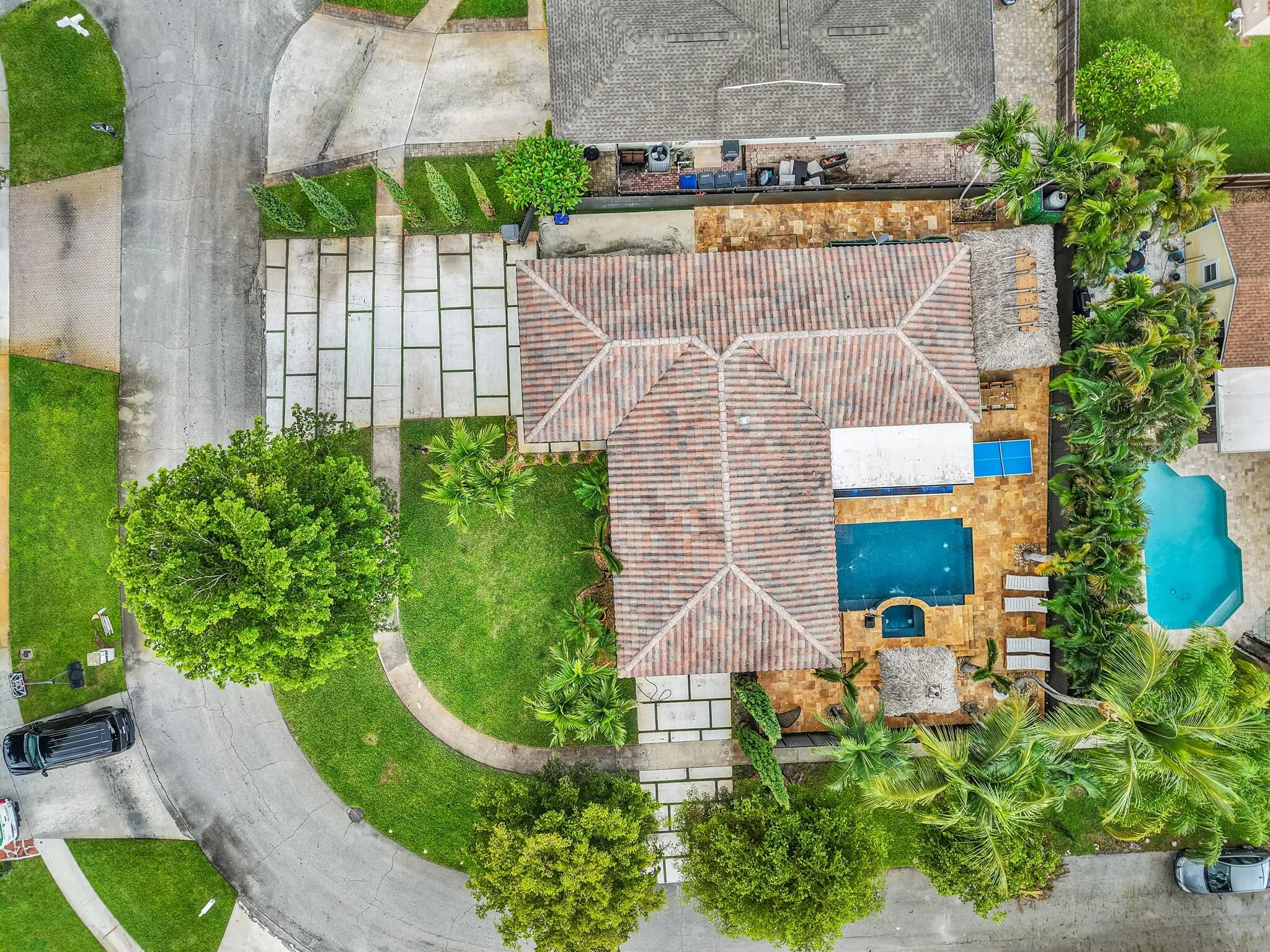Tile roof, geometric paver driveway, manicured lawn, swimming pool, and spa