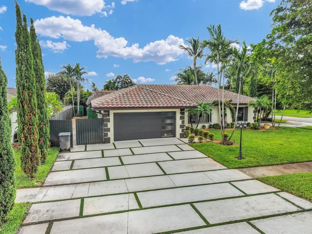 Mediterranean-style residence featuring a tile roof, a modern garage door with frosted glass panels, and a concrete paver driveway with turf accents