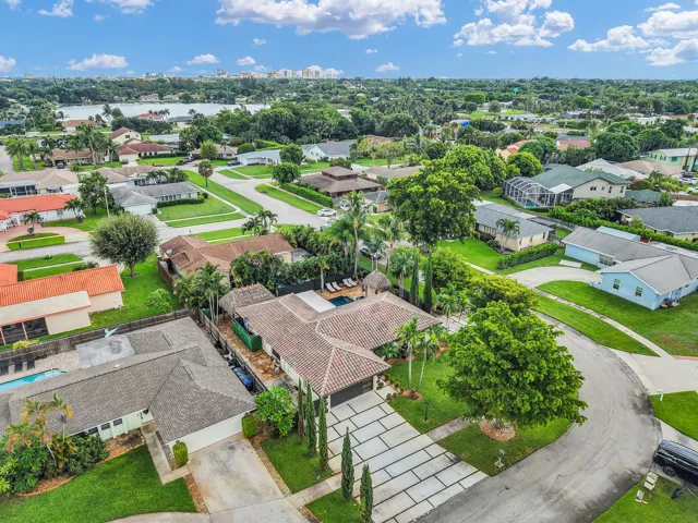 Aerial perspective of a neighborhood featuring a water body, mature landscaping, and a curvilinear street layout