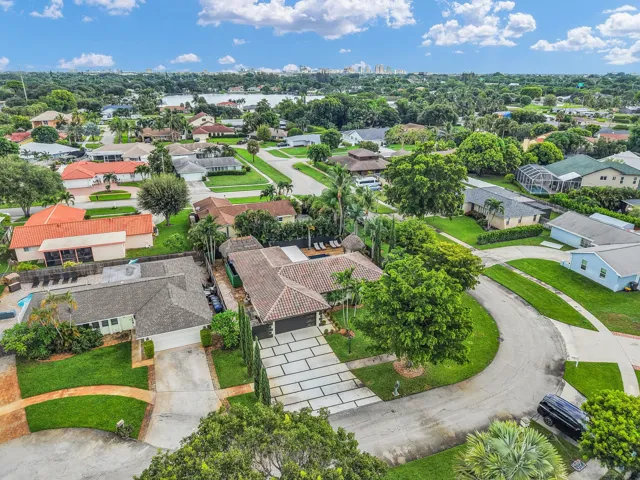 Expansive suburban neighborhood with mature trees, a curvilinear street layout, and a distant body of water