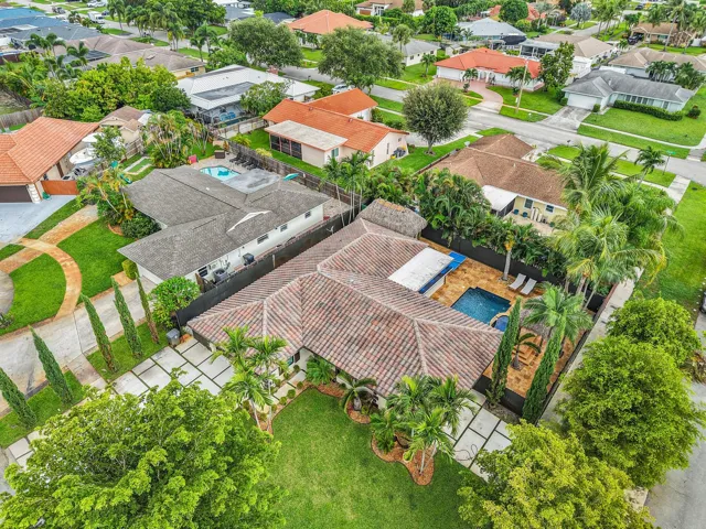 Tiled roofing, private swimming pool, paver patio, lush landscaping, and mature trees