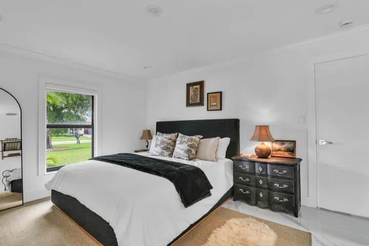Recessed lighting, crown molding, white walls, black-framed window, and a white door with a modern handle