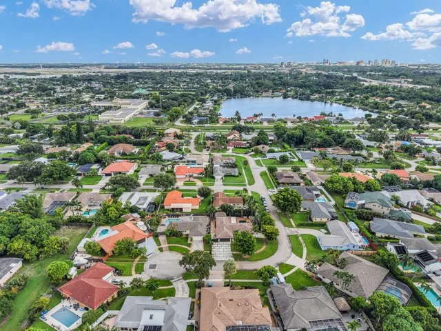 Residential community featuring a prominent central lake, mature trees, and a variety of architectural styles