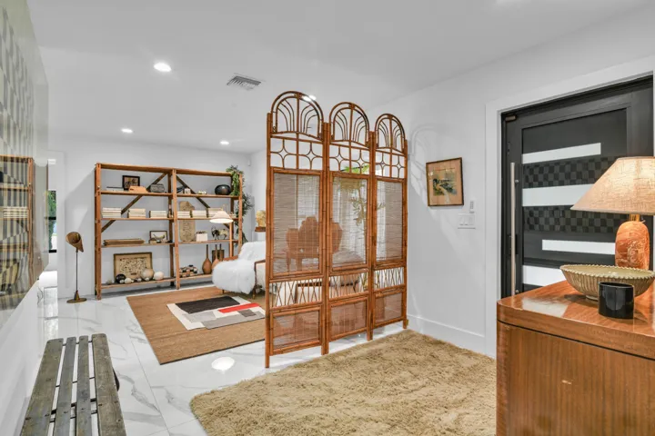 White marble-look flooring, built-in wooden shelving, and a modern black door with horizontal panels