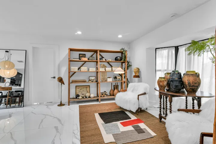 White walls with recessed lighting, large bay window with dark trim, white tile flooring, and built-in wooden shelving