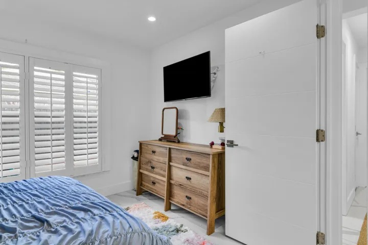Plantation shutters, recessed ceiling lighting, wall-mounted television, and a flat-panel interior door