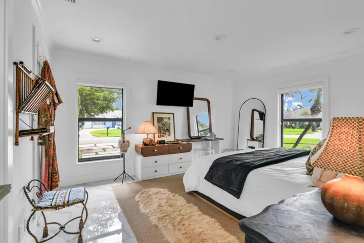 Recessed lighting, large windows with black framing, crown molding, and white tile flooring