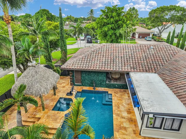 Exterior featuring a tile roof, an integrated pool and spa, a thatched-roof cabana, and extensive hardscaping