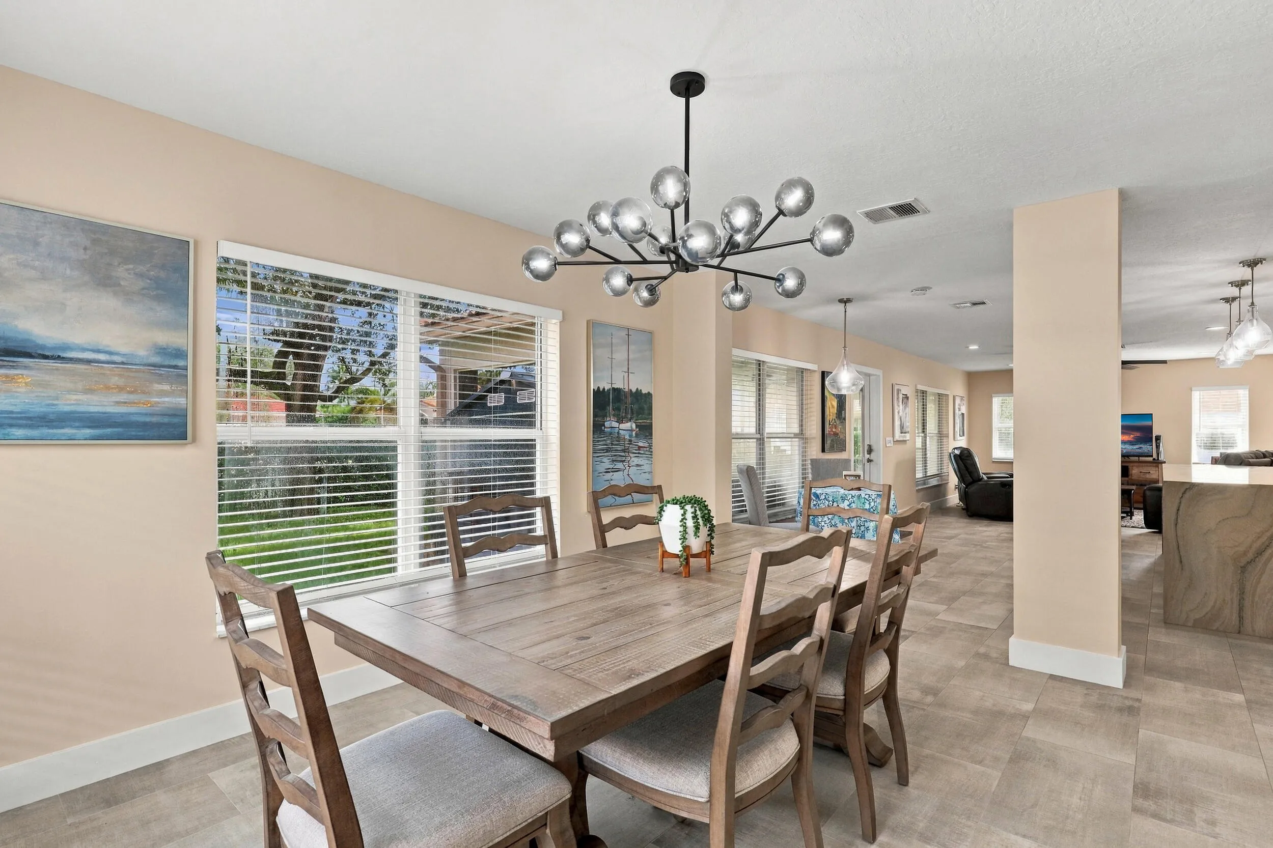 The formal dining room is wrapped in an abundance of light from two oversized windows and highlighted by a designer chandelier.