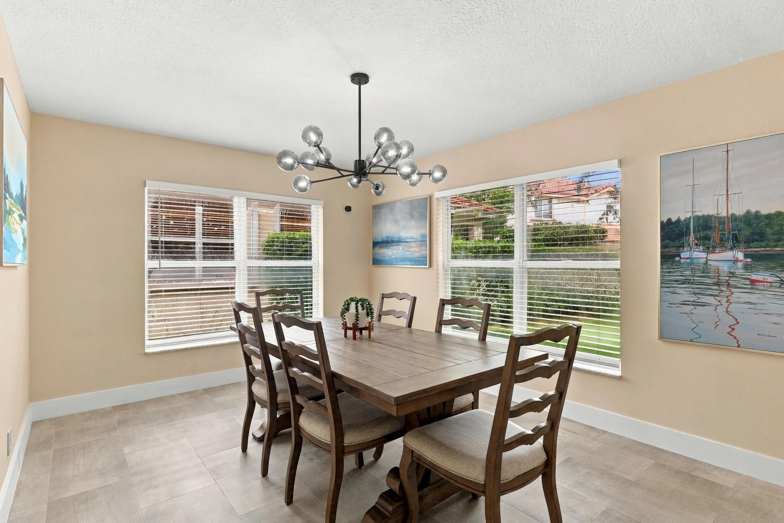 The formal dining room is wrapped in an abundance of light from two oversized windows and highlighted by a designer chandelier.