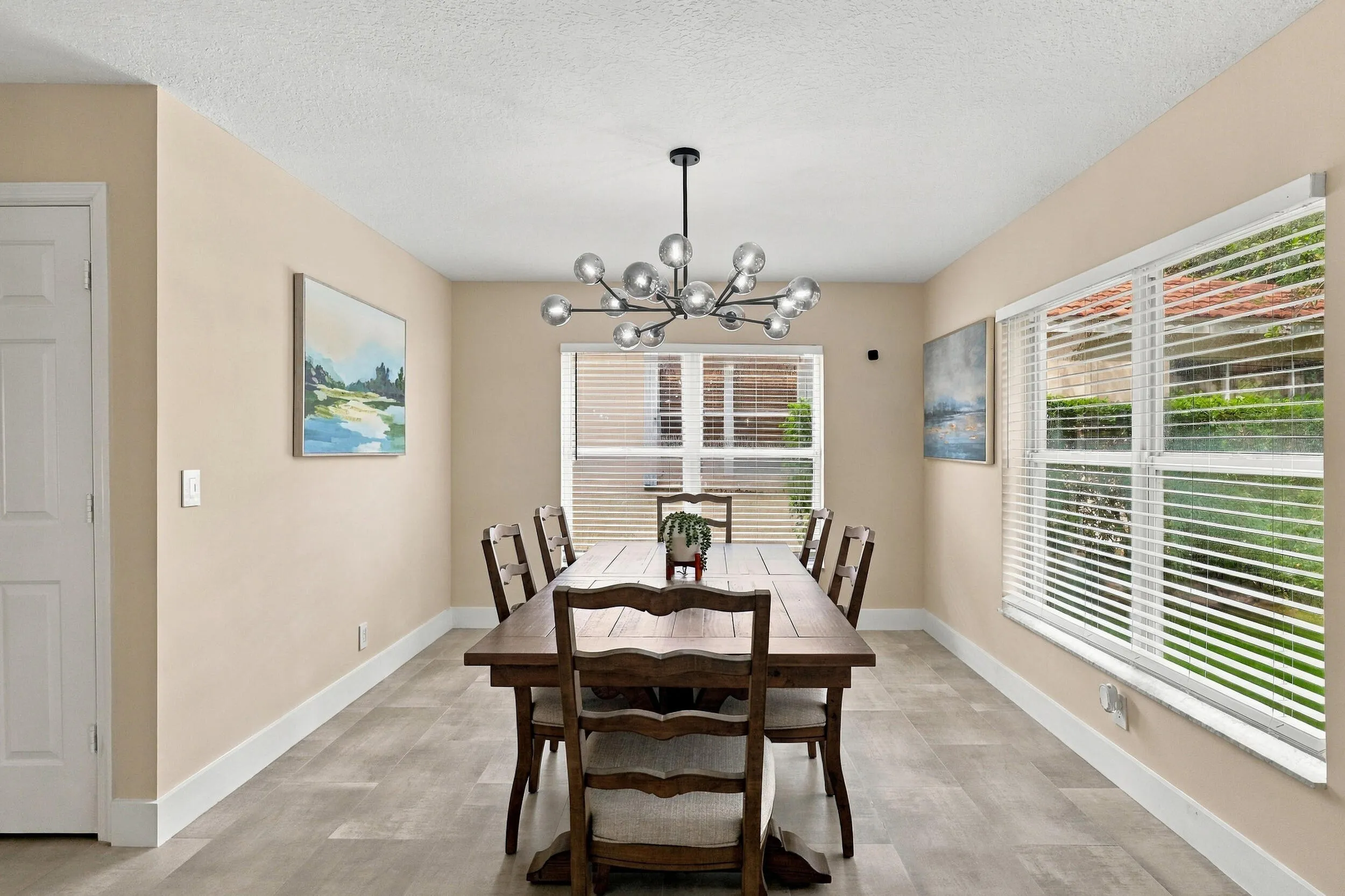 The formal dining room is wrapped in an abundance of light from two oversized windows and highlighted by a designer chandelier.