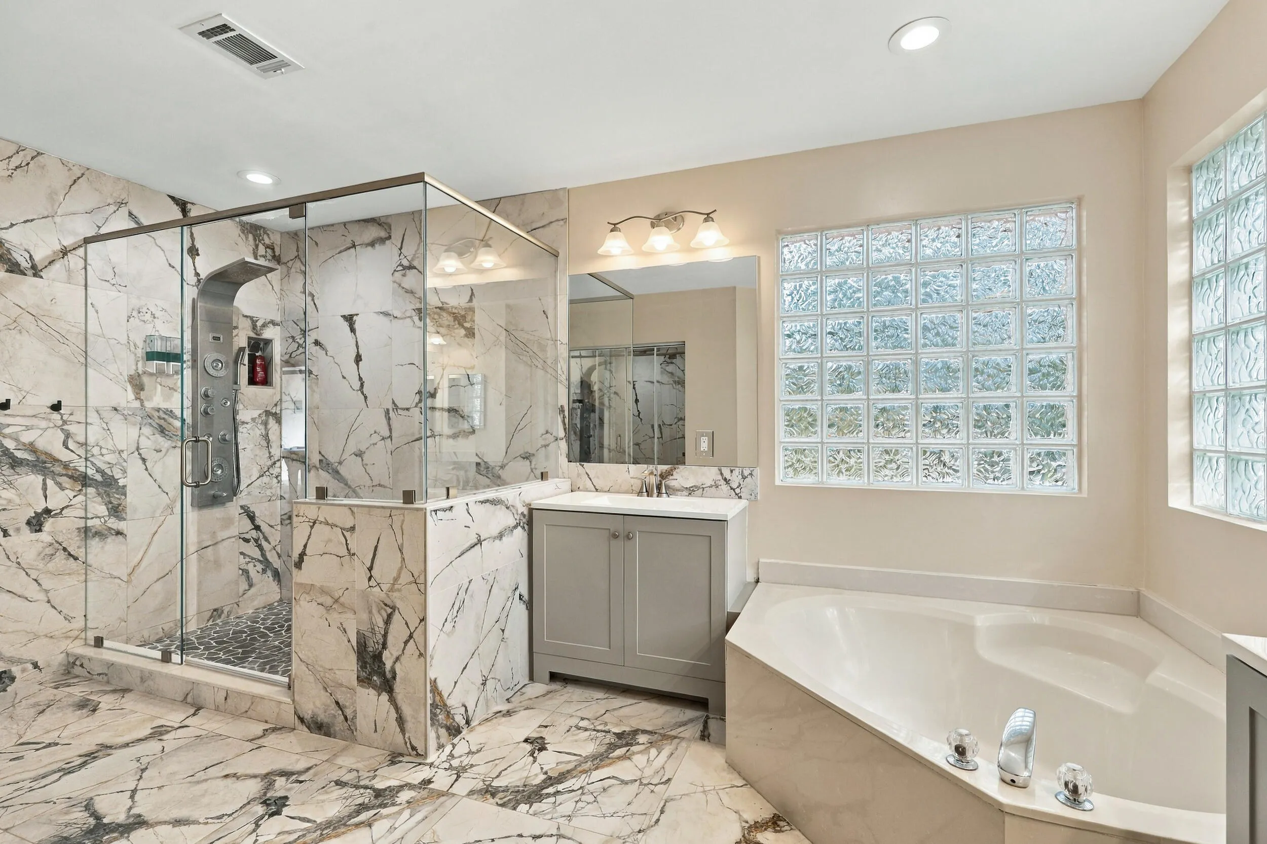 The primary bathroom rivals any five-star spa with a dramatic and elegant, frameless, marble glass shower matching the floors of the bathroom.