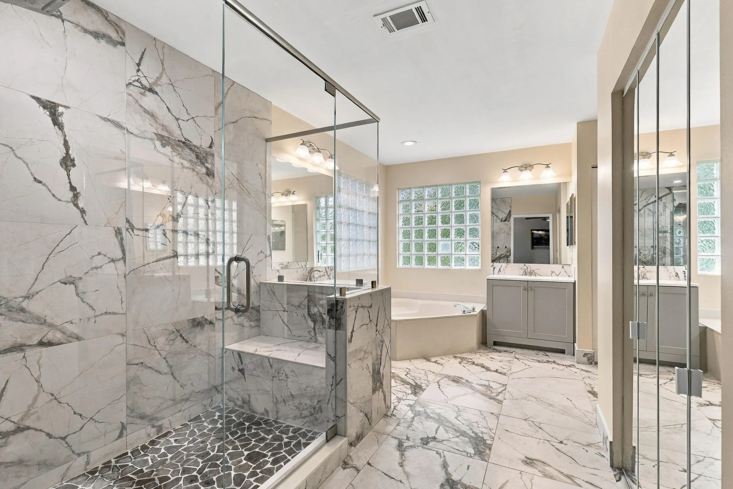 The primary bathroom rivals any five-star spa with a dramatic and elegant, frameless, marble glass shower matching the floors of the bathroom.