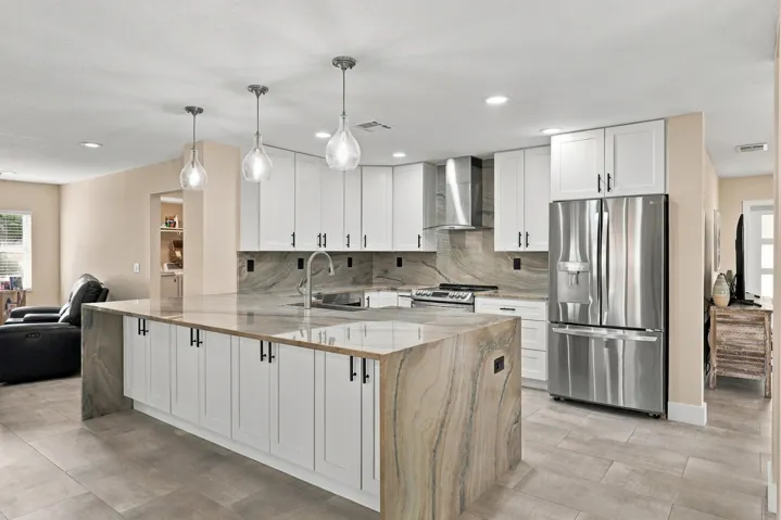 The heart of the home is the exquisite renovated kitchen, featuring white Shaker style cabinetry, stunning quartzite countertops and backsplash, stainless steel appliances, designer lighting, abundant storage, and an oversized island that creates an impressive centerpiece for everyday living and entertaining. The open layout flows effortlessly into the main living areas and breakfast nook, while a separate dining space provides plenty of room for gatherings.