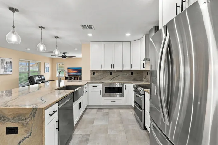 The heart of the home is the exquisite renovated kitchen, featuring white Shaker style cabinetry, stunning quartzite countertops and backsplash, stainless steel appliances, designer lighting, abundant storage, and an oversized island that creates an impressive centerpiece for everyday living and entertaining. The open layout flows effortlessly into the main living areas and breakfast nook, while a separate dining space provides plenty of room for gatherings.