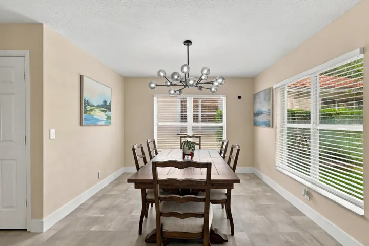 The formal dining room is wrapped in an abundance of light from two oversized windows and highlighted by a designer chandelier.