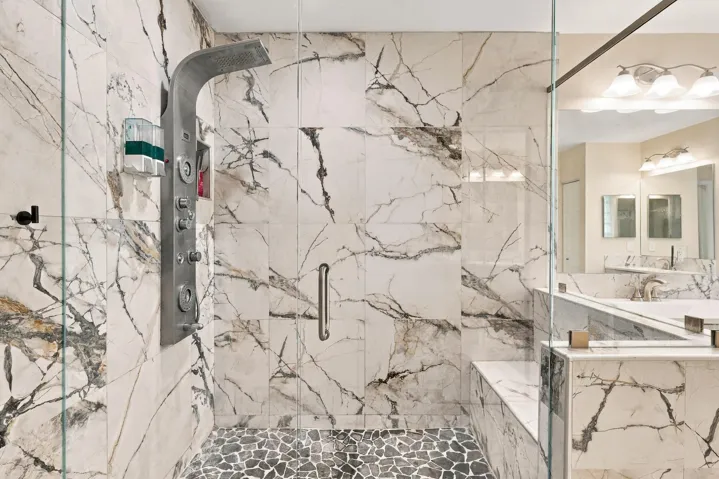 The primary bathroom rivals any five-star spa with a dramatic and elegant, frameless, marble glass shower matching the floors of the bathroom.