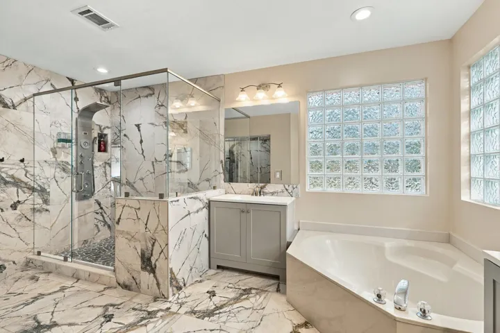 The primary bathroom rivals any five-star spa with a dramatic and elegant, frameless, marble glass shower matching the floors of the bathroom.