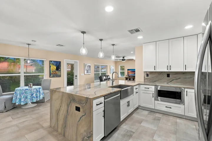 The heart of the home is the exquisite renovated kitchen, featuring white Shaker style cabinetry, stunning quartzite countertops and backsplash, stainless steel appliances, designer lighting, abundant storage, and an oversized island that creates an impressive centerpiece for everyday living and entertaining. The open layout flows effortlessly into the main living areas and breakfast nook, while a separate dining space provides plenty of room for gatherings.
