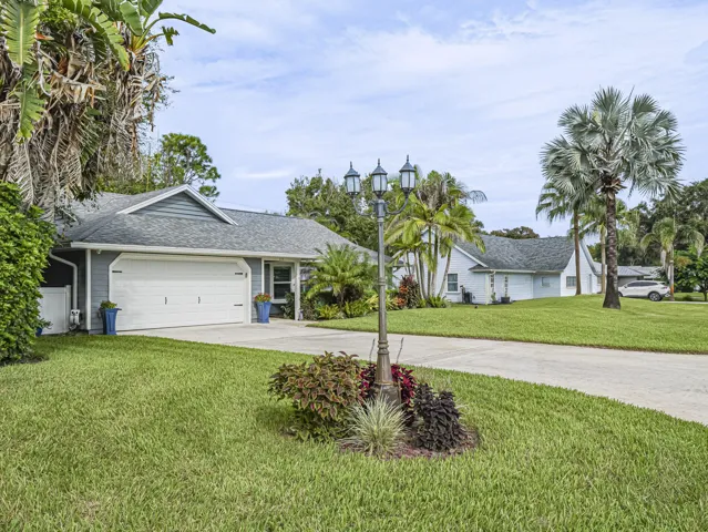 Manicured lawn, mature landscaping, a concrete driveway.