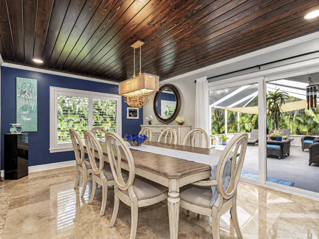 Wood-plank ceiling with impact sliding glass doors opening to an enclosed patio.