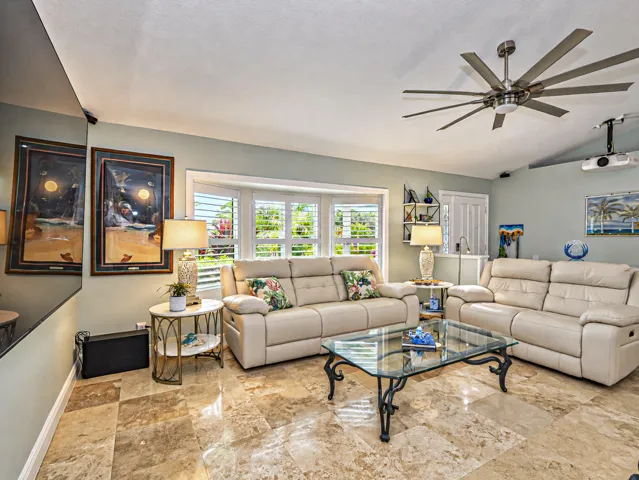 Great living space, travertine floor, bay window with plantation shutters, ceiling fan, built-in projector