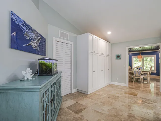 Vaulted ceiling, full-height built-in cabinetry, bi-fold closet doors, tile flooring, and a cased opening