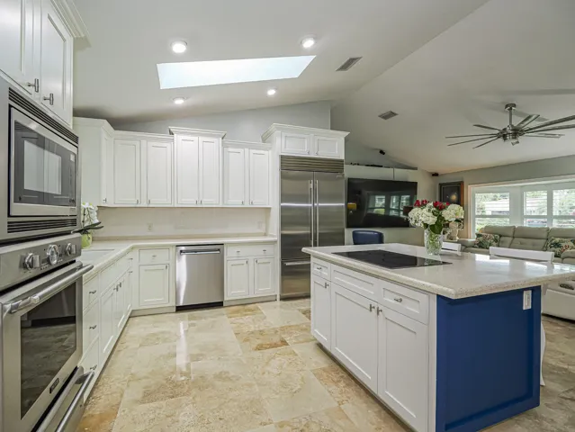 White cabinetry, stainless steel appliances, central island with cooktop
