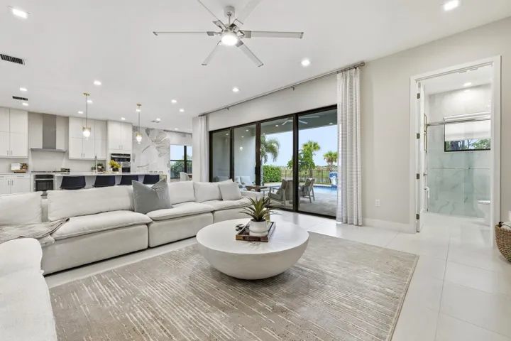 Open concept living area with recessed lighting, ceiling fan, large format tile flooring, and sliding glass doors to the exterior