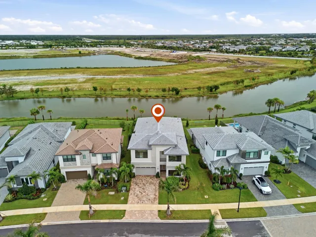 Two-story residence with a gray tile roof, light-toned exterior, paved driveway, and established landscaping