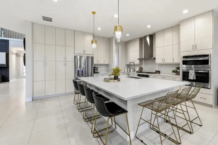 Gourmet kitchen featuring a substantial island with countertop, stainless steel appliances, extensive cabinetry, tile flooring, and integrated pendant lighting