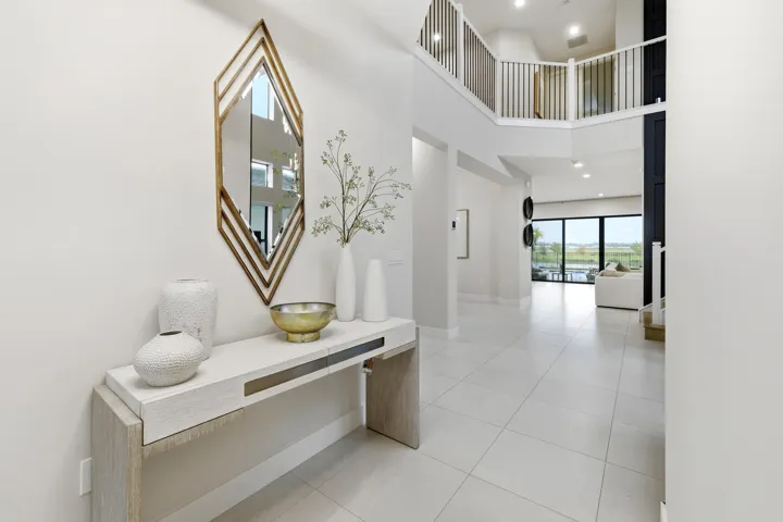 Two-story entry foyer featuring large format tile flooring and a second-story balcony with metal railings