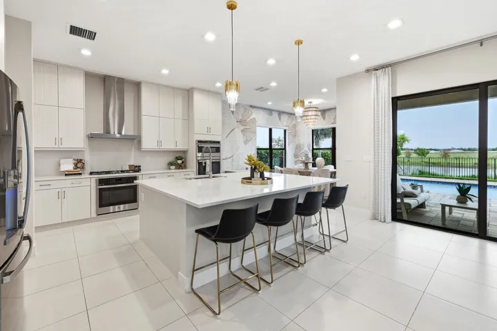 Modern kitchen featuring light-toned cabinetry, stainless steel appliances, a large center island with seating, and tile flooring