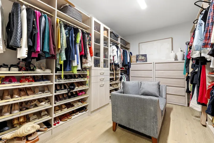 Custom closet system with extensive shelving, multiple hanging rods, built-in drawer storage, and glass-front cabinetry