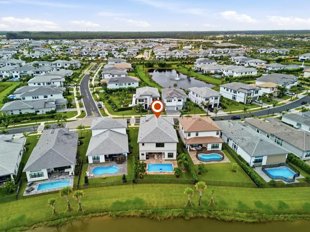 Rear exterior featuring a private pool, covered patio, fenced yard, and direct access to a water feature