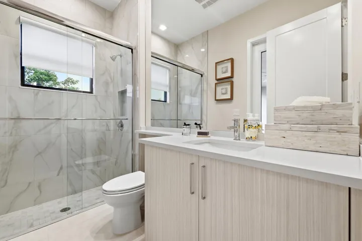 Walk-in shower with glass enclosure, integrated shower niche, and large format wall tiling