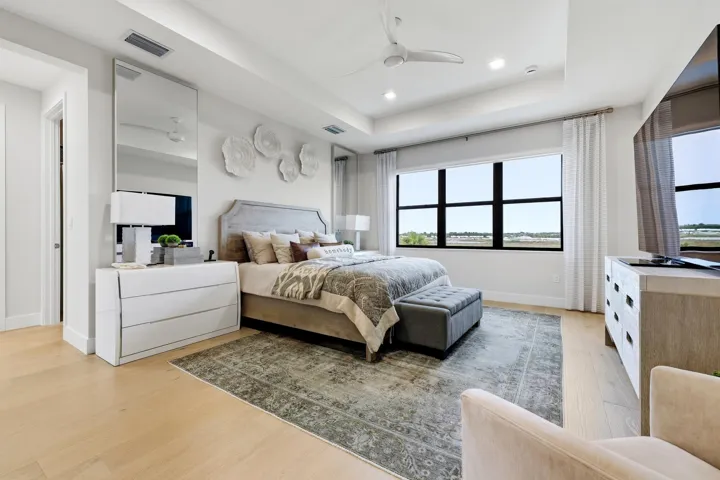 Light wood-finish flooring with a tray ceiling and recessed lighting