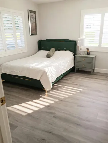 Wood-finish flooring, neutral wall tones, and white plantation shutters