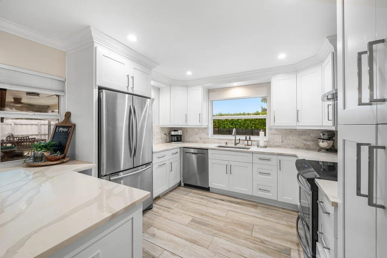 White cabinetry, stainless steel appliances, and a window above the sink brighten the kitchen.
