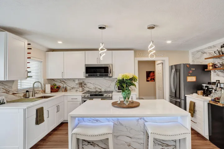 Fully updated kitchen with waterfall island, stone countertops and stainless steel appliances