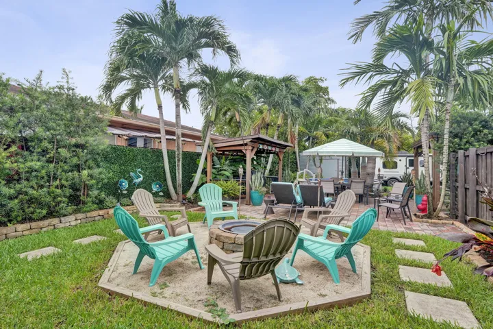 Expansive backyard featuring a stone fire pit, mature palm trees, and a paved patio area