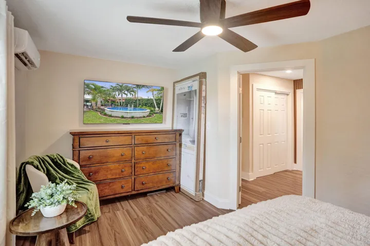 Wood-finish flooring with a ceiling fan light fixture, and an in-wall air conditioning unit