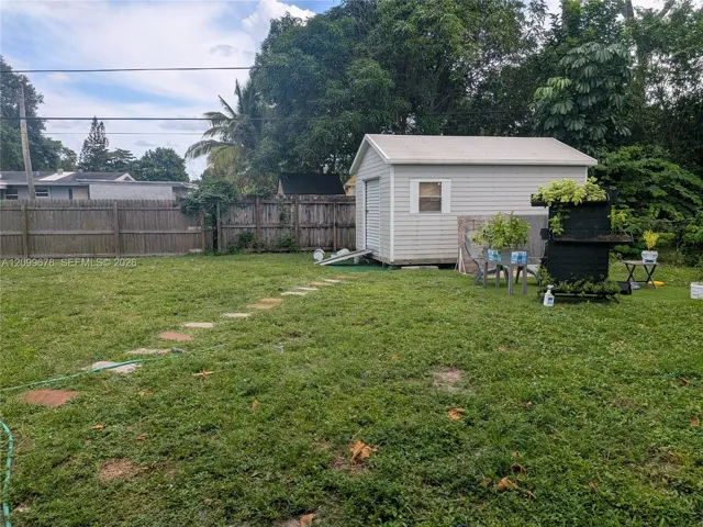 Backyard featuring a vinyl-sided storage shed, a stone paver pathway, and wood privacy fencing