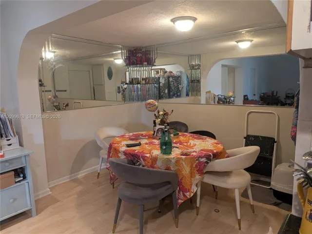 Large wall-mounted mirror, arched architectural openings, and light-tone wood-finish flooring