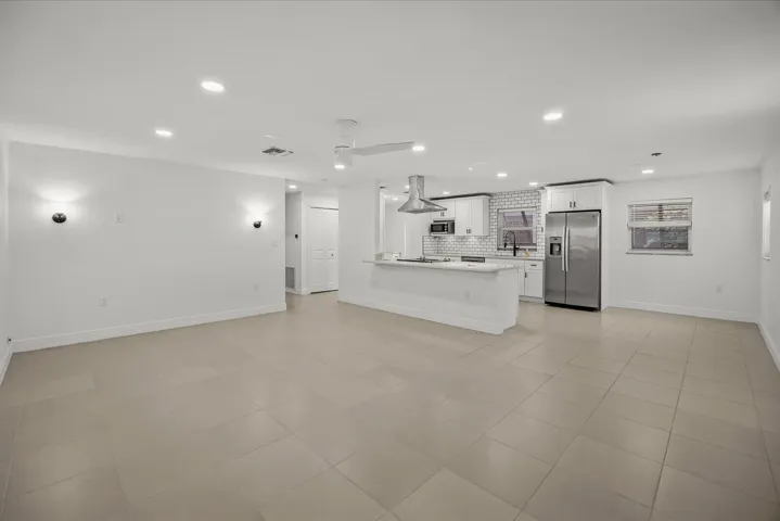 Recessed lighting, tile flooring, kitchen island with counter seating, stainless steel appliances, and white cabinetry