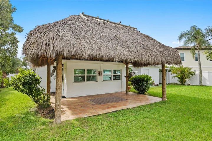 Thatch-roofed structure with wood-post supports, concrete block walls, and multiple windows