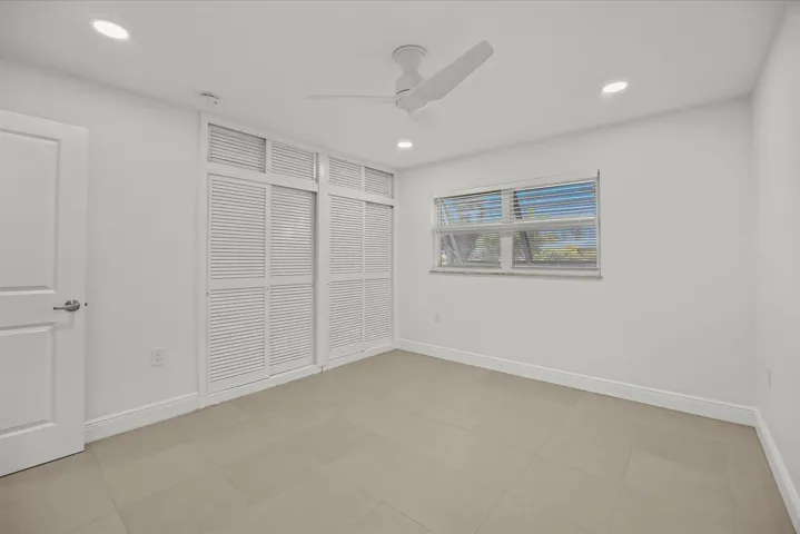 Recessed lighting, ceiling fan, white paneled door, shuttered closet doors, and tile flooring