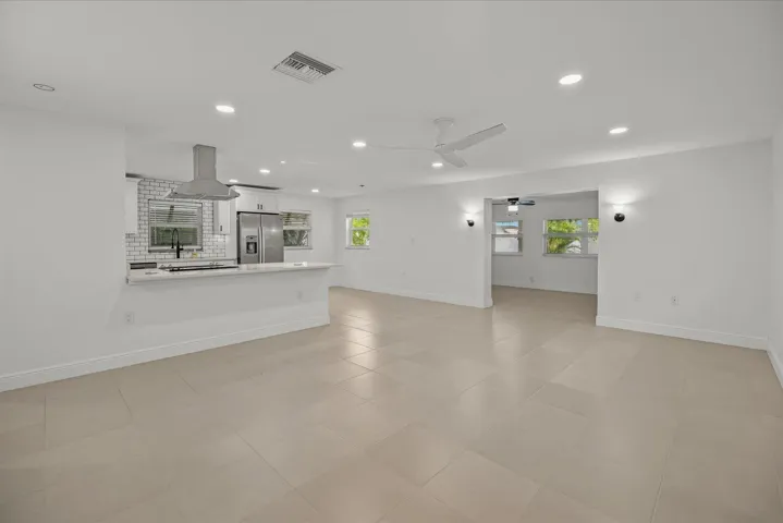 Open-concept living area featuring light-toned tile flooring, recessed lighting, and a ceiling fan