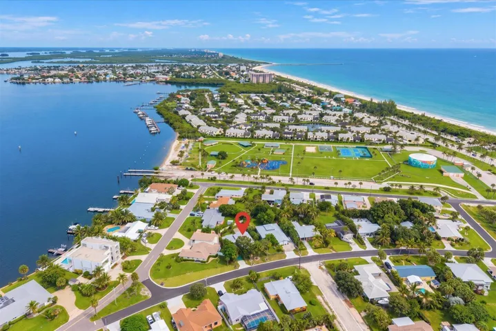 Waterfront community with direct access to a large body of water, featuring a sandy beach, multiple boat slips, and a public park with recreational amenities